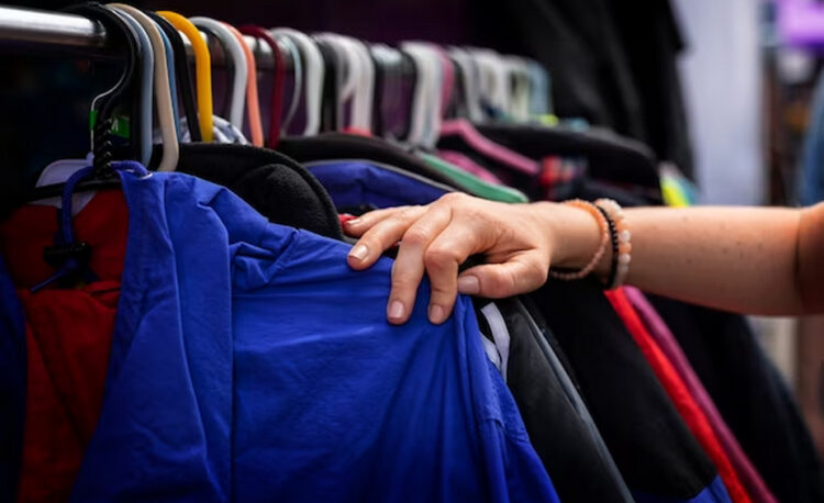 A hand browsing through hung sports apparel in a sports shop.