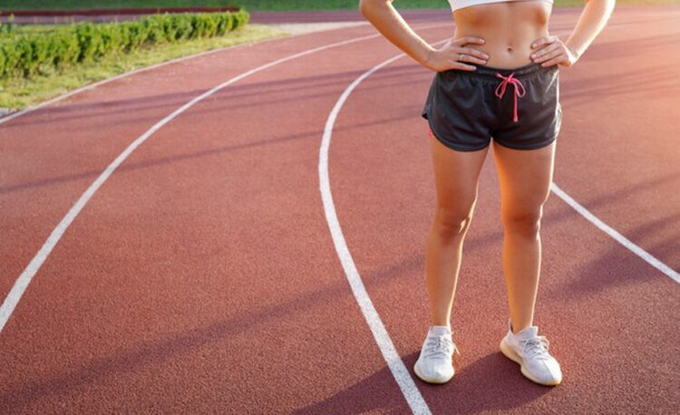 Woman in sports attire on a running track.